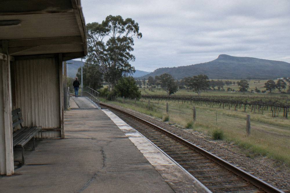 A country railway platform on the Hunter line with open farmland beyond