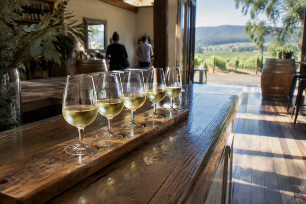 A tasting flight of white wines lined up on a timber cellar door bar