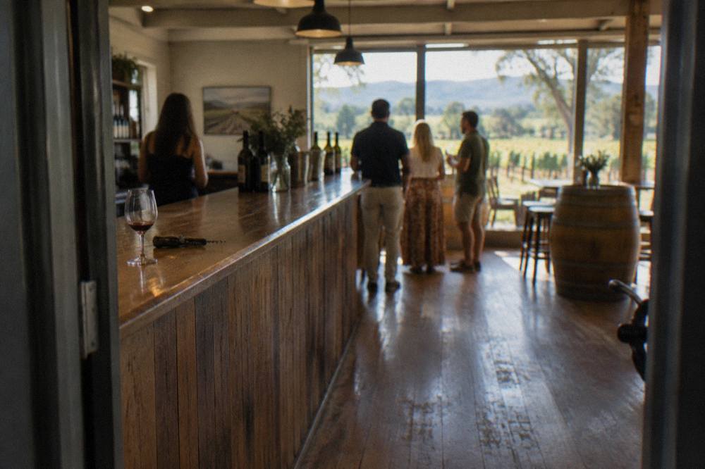 A small group tasting wine at a wooden cellar door bar