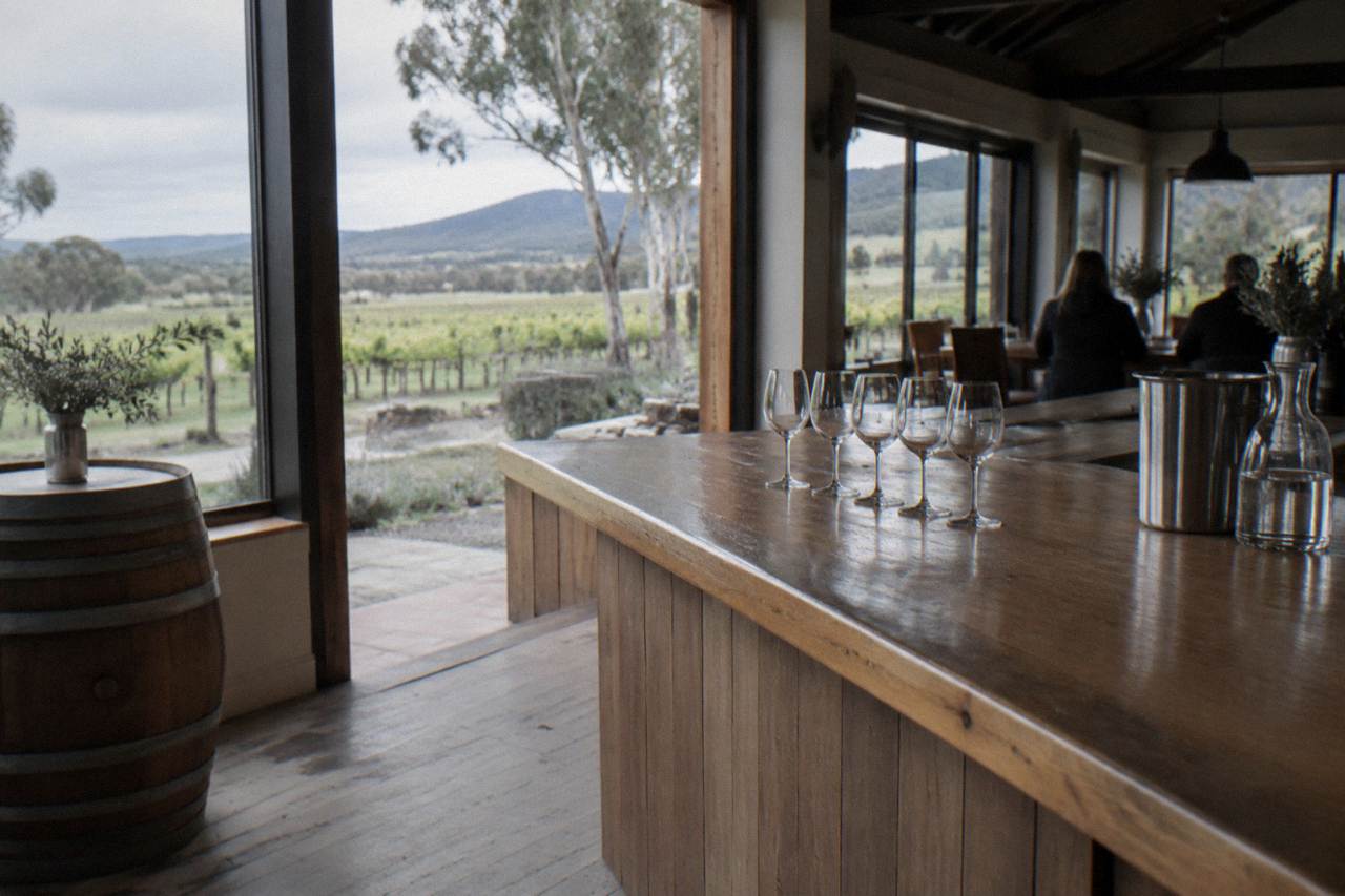 A timber cellar door tasting counter with rows of wine glasses ready for a tasting flight