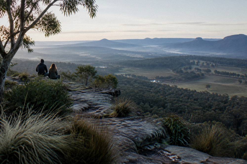 Sandstone escarpment lookout over forested valleys with morning haze