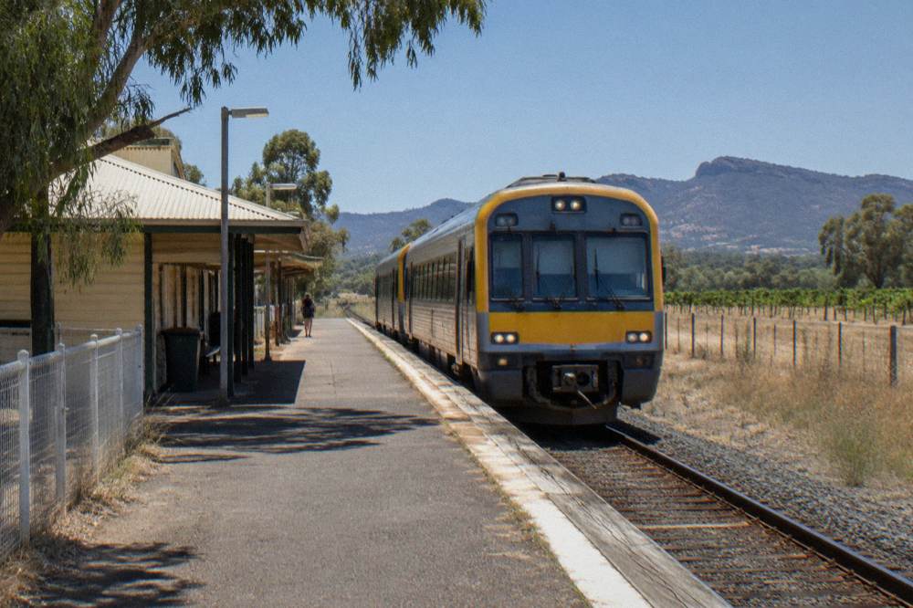 Country railway platform with a waiting regional train under a clear sky
