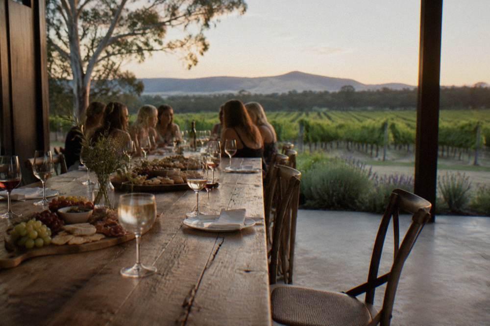 A long wooden table set with sharing platters and wine glasses inside a rustic tasting room