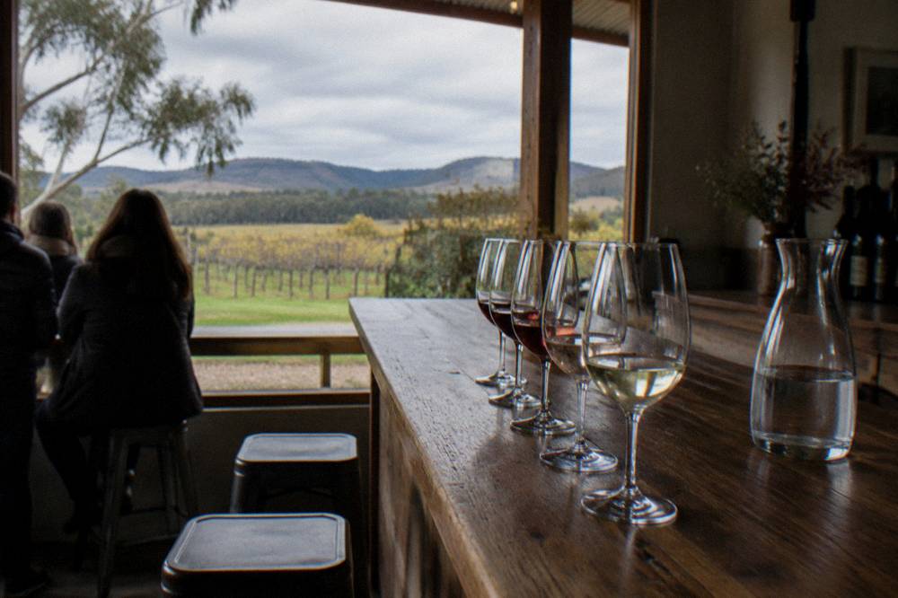 A small group of tasting glasses lined along a timber cellar door bar counter