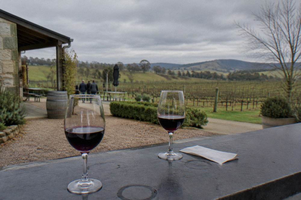 Tasting fee notes and a receipt beside glasses of red wine on a cellar door counter