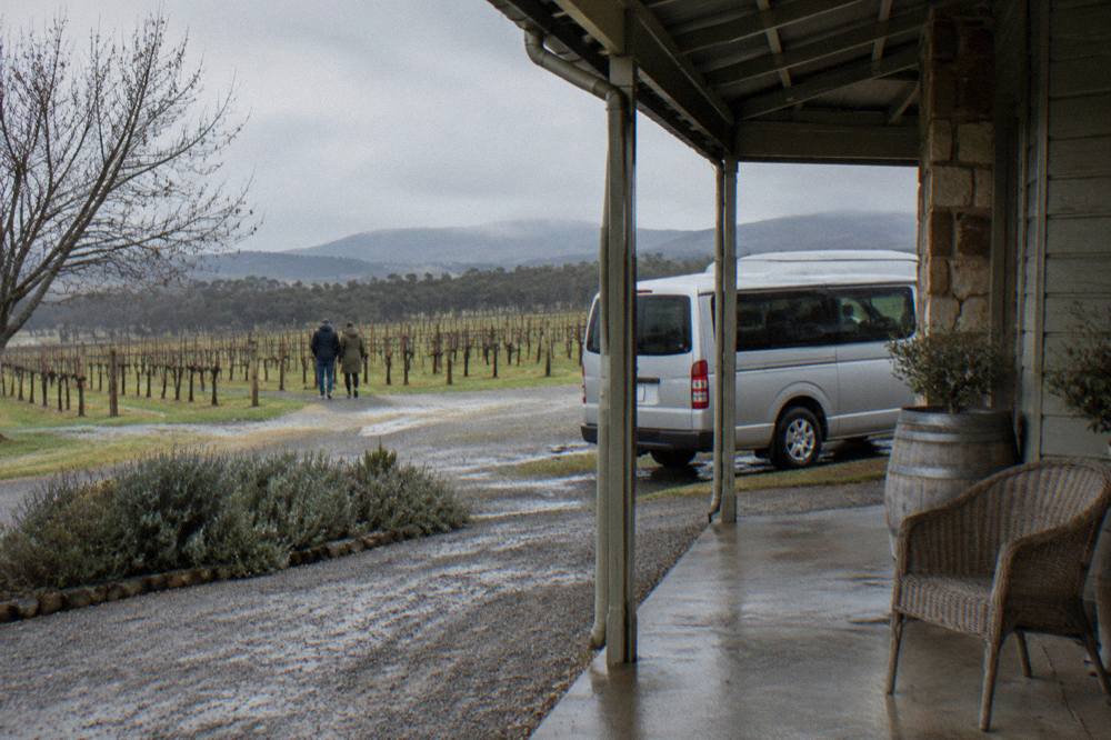 A private touring van parked on a gravel driveway beside a small cellar door building